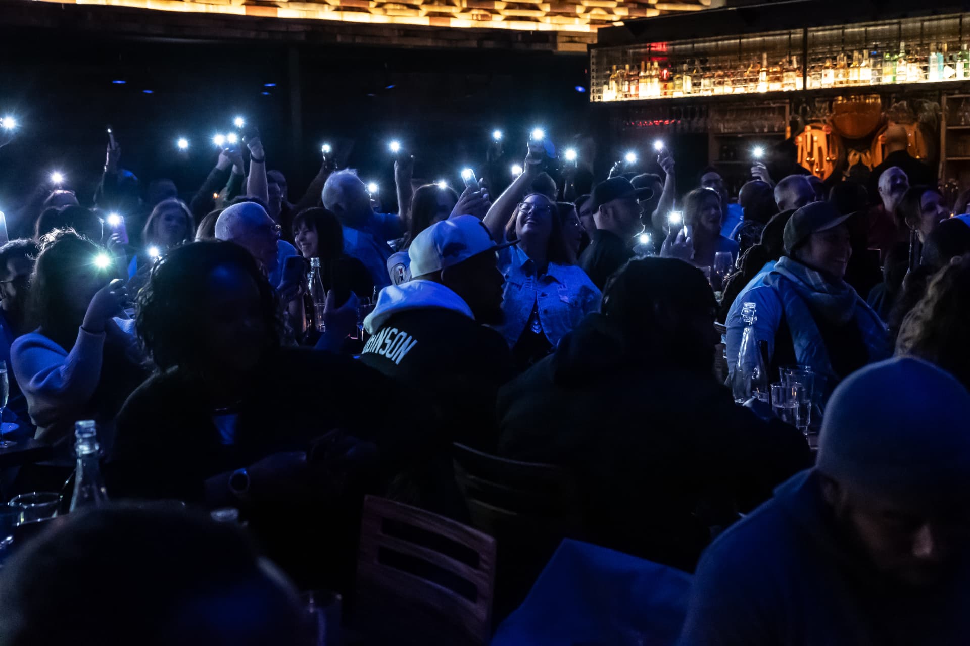 Crowd holding up phone flashlights in a dark room